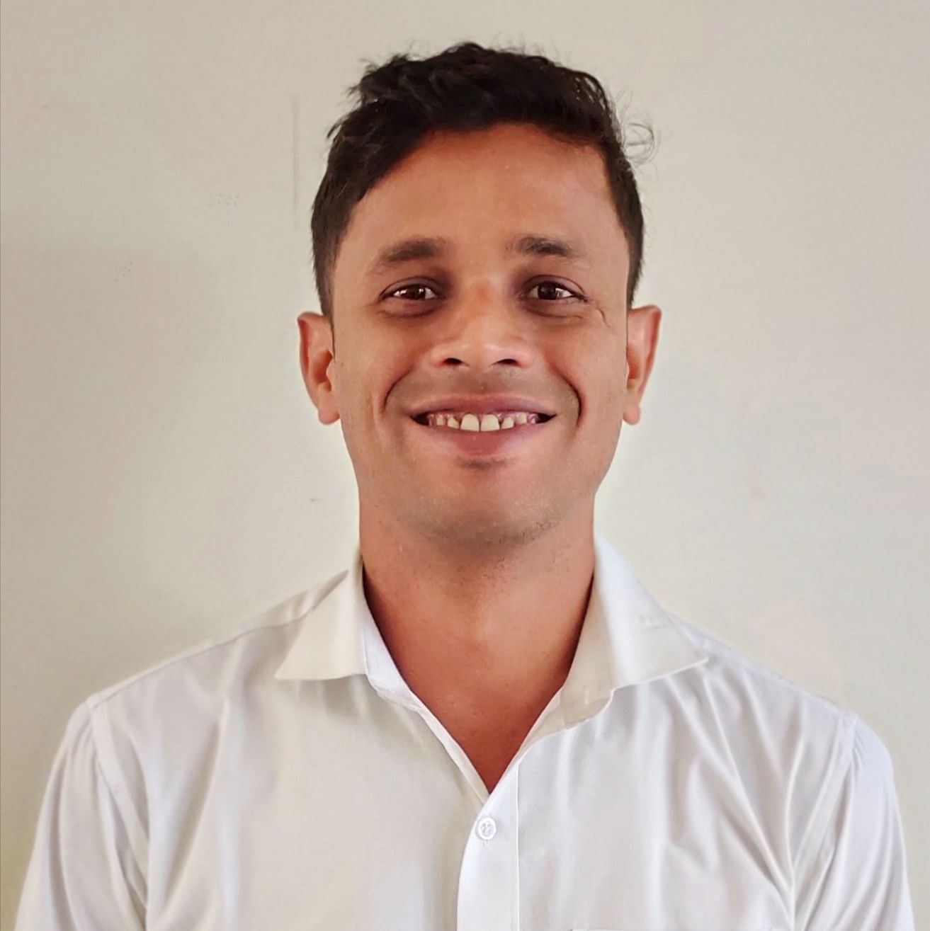 A young man with a short haircut and a white collared shirt smiles at the camera