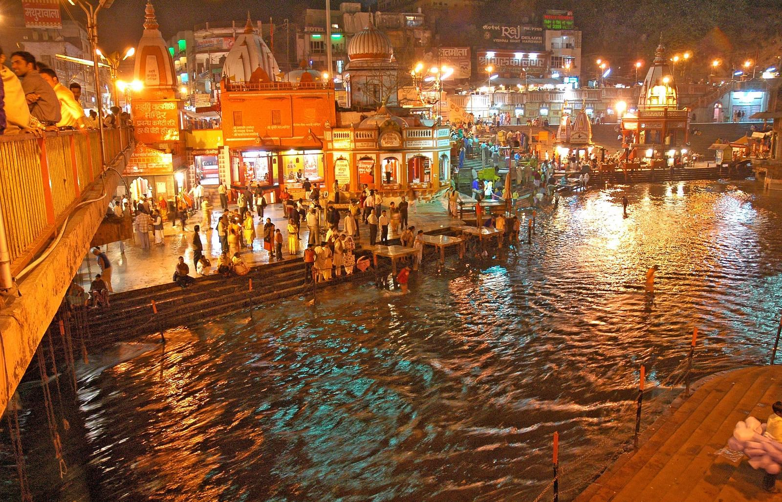 The image features a wide angle view of illuminated city with a lake in the night
