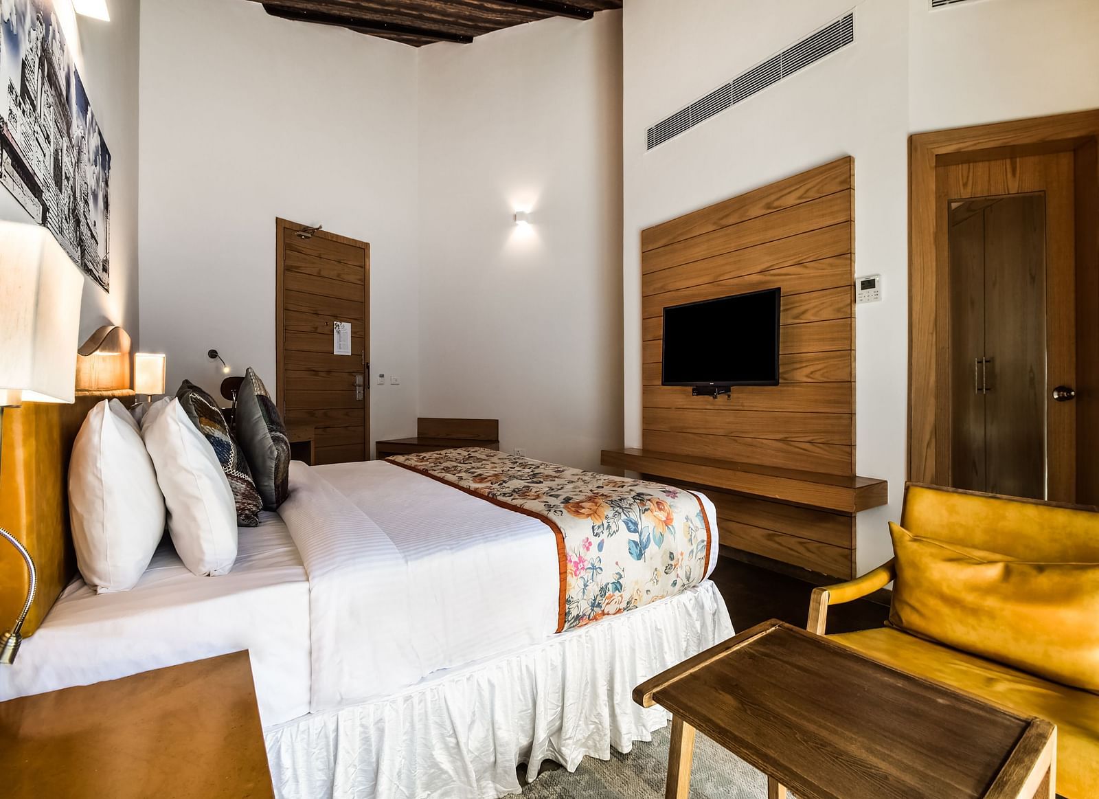 A modern bedroom with a plush bed, a mounted TV, and a armchair.- Bamboo Saa Resort & Spa, Udaipur