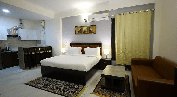 A hotel room with a large bed, kitchenette and seating area, with warm lighting - Lime Tree Golf View, Golf Course Road