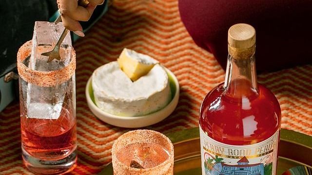 a jin bottle kept on a wooden table along with a few filled glasses - Villa in Palms by V Escapes