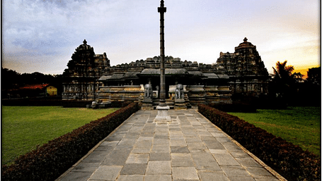 A pathway leading to Belur Temple designed with Hoysala Architercture with a colourful sunset in the backdrop.