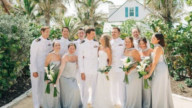 Group poses for a wedding photo among palm trees at Abaco Inn, bride and groom at the center.