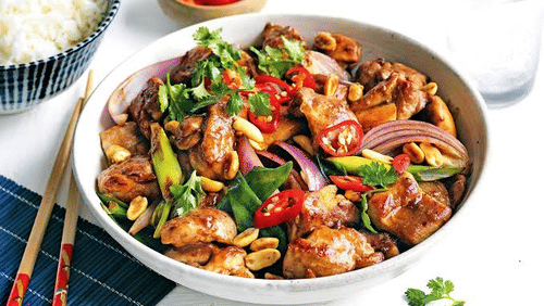Kung Pao Chicken served in a bowl with chopsticks placed beside it at Hotel Uday Palace.