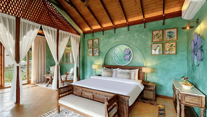 A beautiful bedroom in a villa featuring a patterned wall behind the headboard of the plush double bed - Golden Tulip Goa Mandrem
