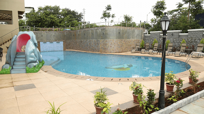 An image of a swimming pool and beside it there are seating area - VITS Lonavla