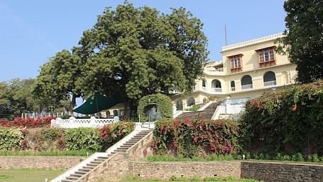 A facade image of Brijraj Bhawan Palace Hotel seen from the lawn