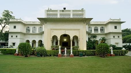 A facade image of Hari Mahal Palace with a well mainted lawn infront