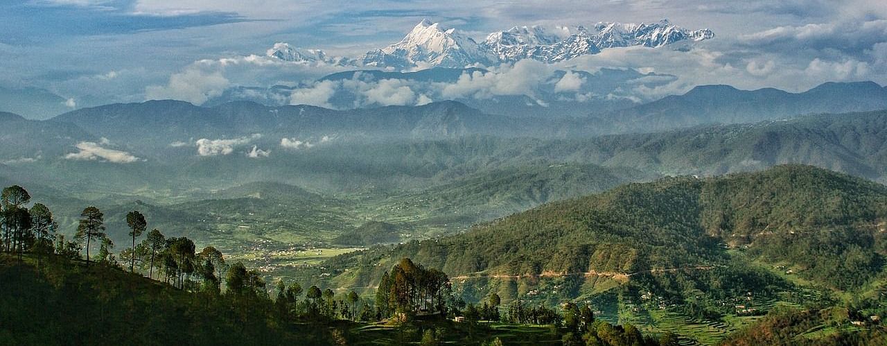 A panoramic view of a mountain landscape with clouds and colorful flags, showcasing a beautiful valley.