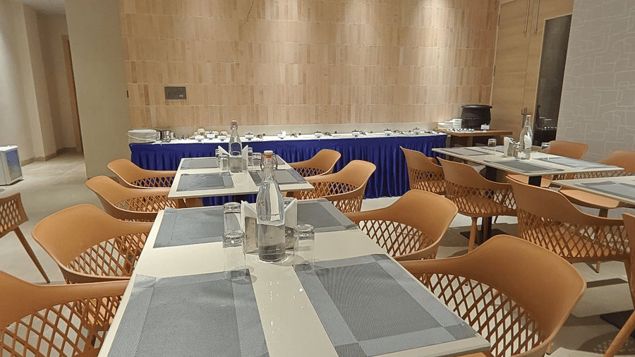 Elegant indoor dining space at Hotel Bluestone Prime with well-spaced tables, coordinated seating, warm-toned walls, and subtle lighting. The uncluttered layout and modern décor enhance comfort and provide a pleasant dining experience.