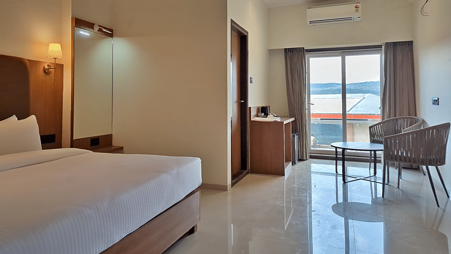Bedroom with a double bed, seating area, and glass doors opening to a balcony.