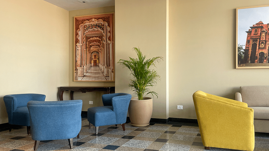 A hotel lobby seating area with blue and yellow armchairs, a couch, a framed artwork, and a potted plant - Urban Suites by BluSalzz, Jaipur