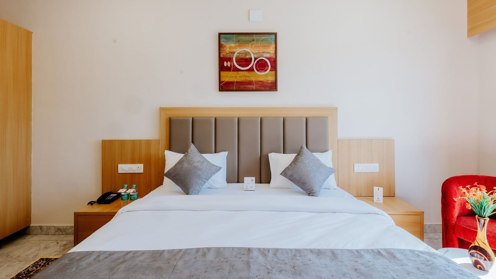 Front view of an inviting bedroom at Daksh The Grand Gowardhan, Dwarka, featuring a plush double bed along with a cushioned headboard.