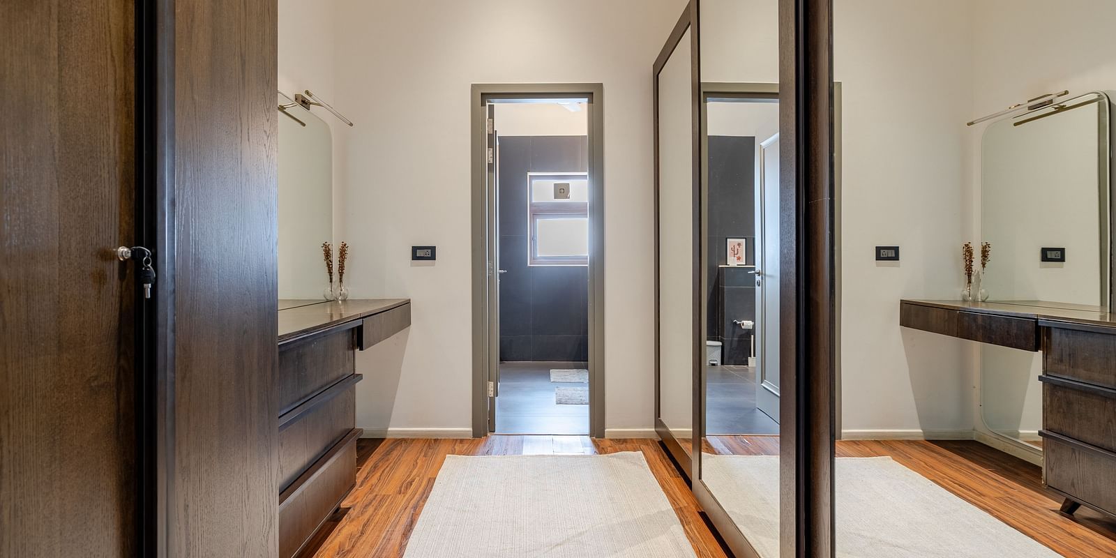 Spacious dressing area at Lindsay Manor with wardrobes, mirrors, and access to the bathroom and other spaces.