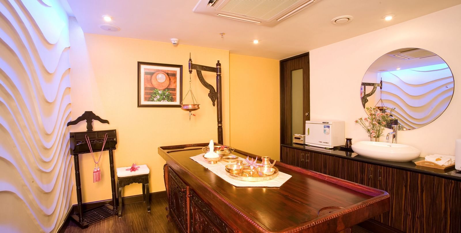 Spa table in front of textured wall side view at Grand Chennai By GRT Hotels.