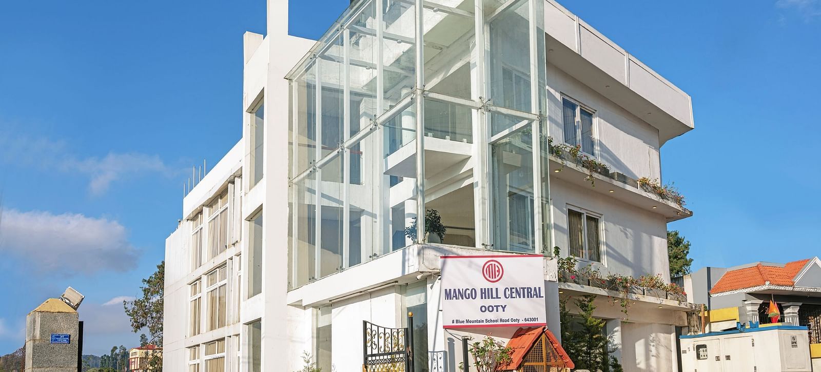 Exterior view of a contemporary white building with glass balconies | Mango HIll Central, Ooty