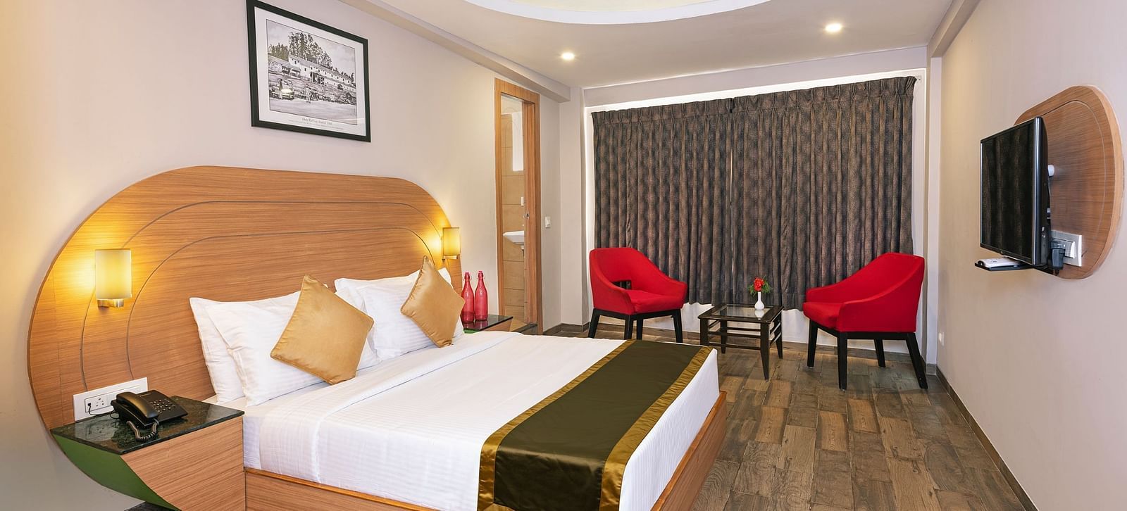 An image of a bedrom with dube sized bed and chairs on a different corner  | Mango HIll Central, Ooty