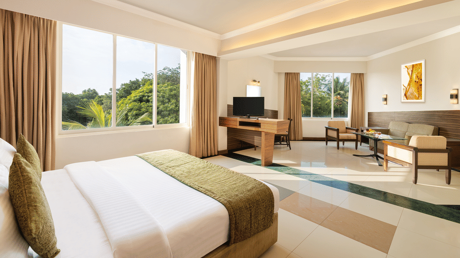 A room with a double bed and sofa seating arrangement at Sangam Hotel, Thanjavur