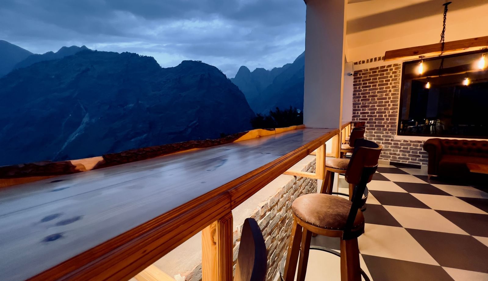image of the bar with black and white titles and elevated chairs overlooking the beautiful mountain ranges in the background - The Tattva Boutique Resort