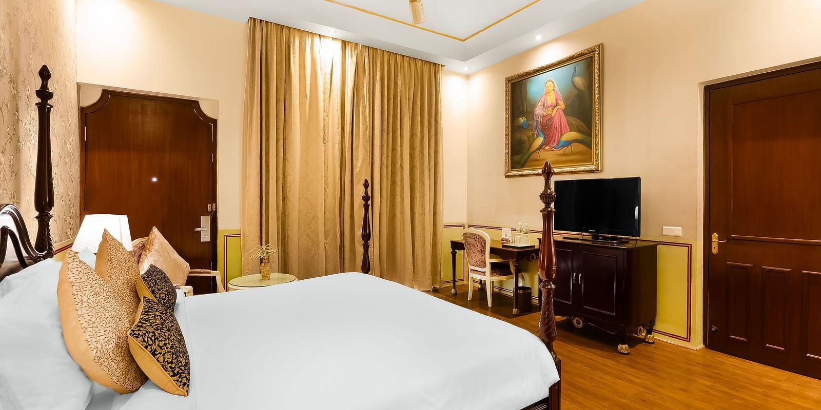 An overview of a room with a double bed, tv and a ceiling fan inside it - Rajasthali Resort & Spa, Jaipur.