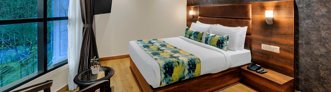 An image of Sumitel Queensyard premium room with king size bed, ceiling fan and an expansive window