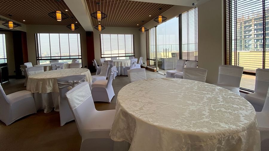 An image of a banquet hall with its seating arrangement and subtle decoration with lighting - Hideaway banquets & Lawns, Greater Noida