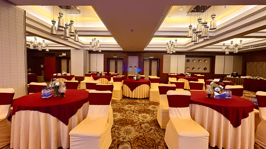 Front view of spacious banquet hall with warm lighting and multiple exits at the far end - Senses Hotel