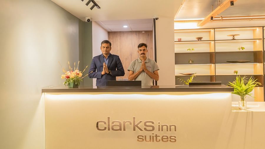 Hotel reception desk with friendly staff, modern interiors, and floral decor at Clarks Inn Suites Jaipur, Ajmer Road