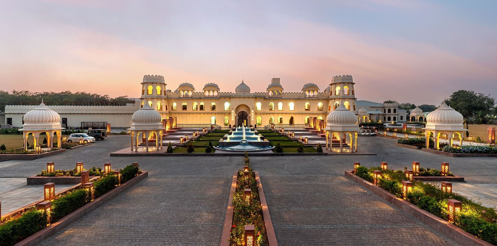 Exterior view of Kesar Bagh Palace building at sunset with landscaped pathways.