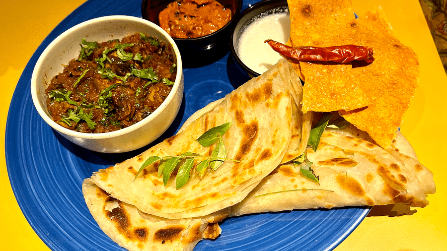 A plate containing Indian bread, gravy, papad, curd, and pickle.