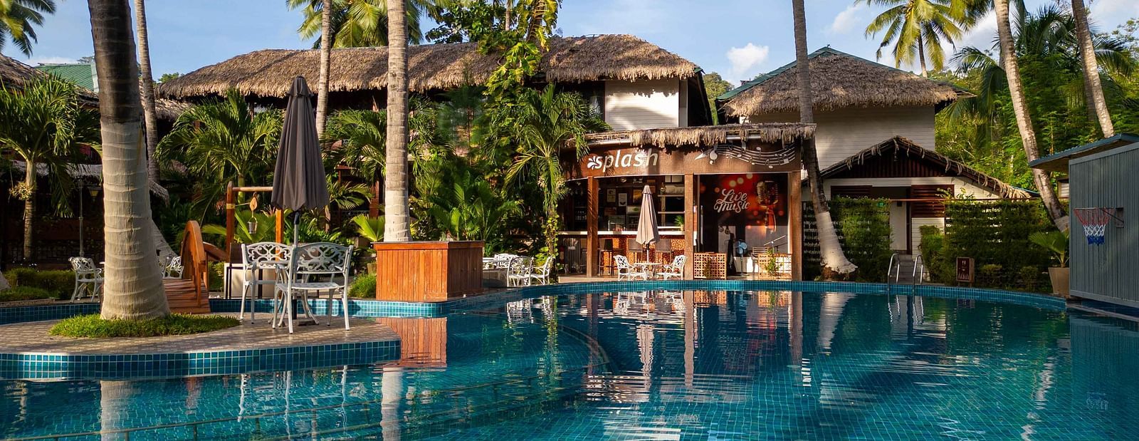  A panoramic view of a resorts outdoor pool area with tropical palm trees and well-maintained gardens surrounding the space. The setting creates a peaceful, relaxing environment - Coral Reef Resort & Spa, Havelock