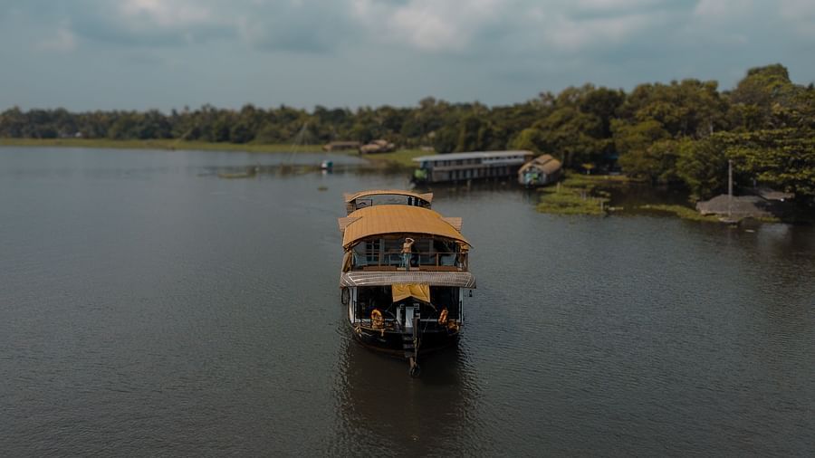 A cruise sailing across the Vembanad Lake with lush greenery in the background - BluSalzz Villas - Muhamma Resort, Alleppey