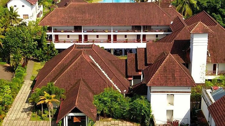 Overhead view of a cluster of buildings with a lake at the far end - Rhythm Kumarakom