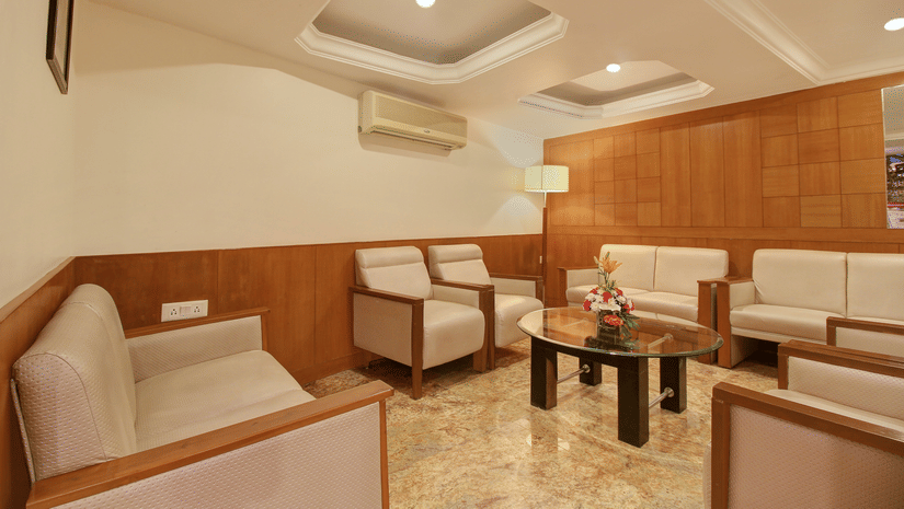 lobby area with a pair of white couch for customers to wait or relax in along with a glass teapoy table in front and a flower vase - the monarch hotel