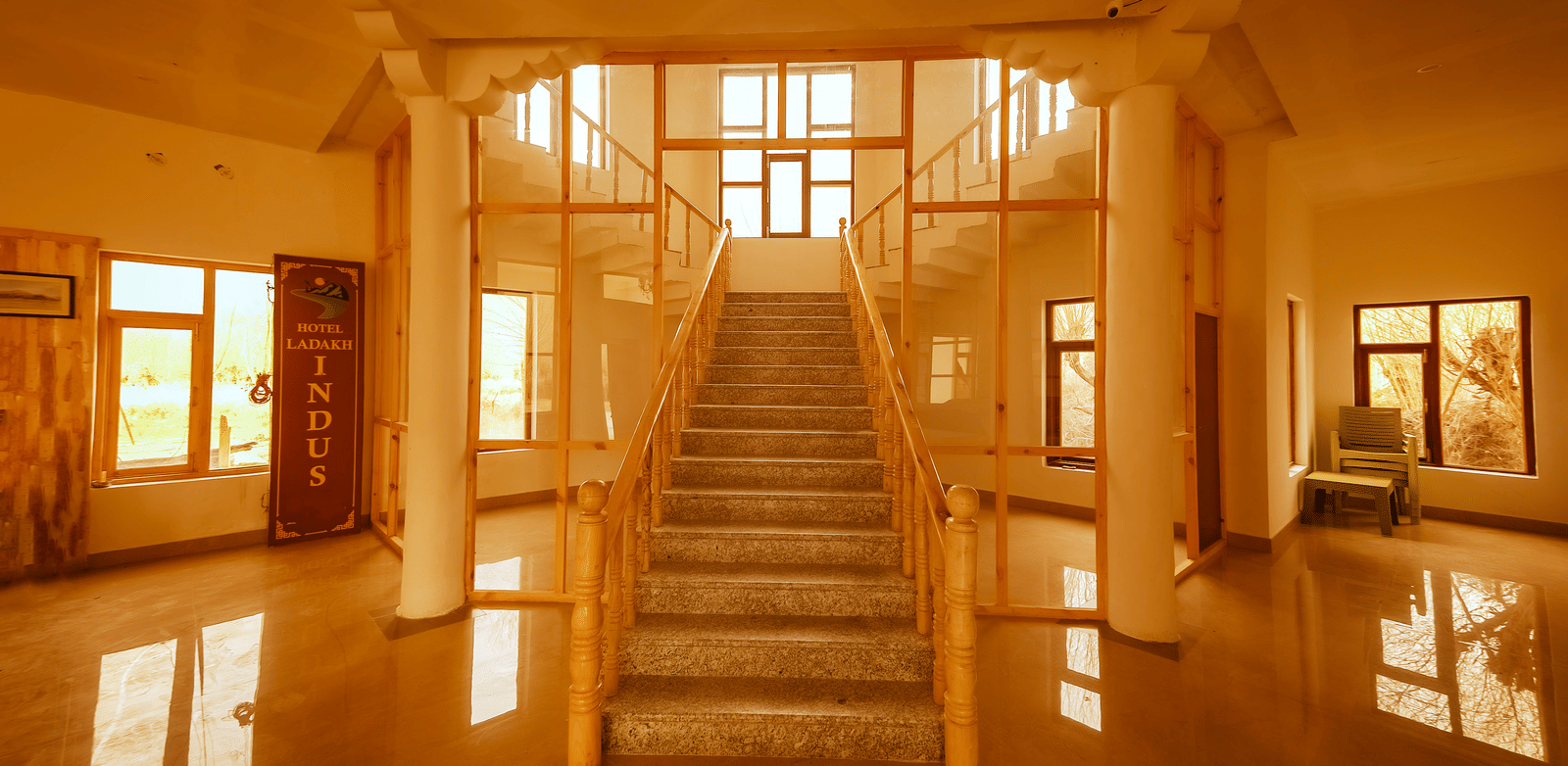 A grand wooden staircase leading upwards in a sun-drenched hallway at Indus Serenity Retreat.