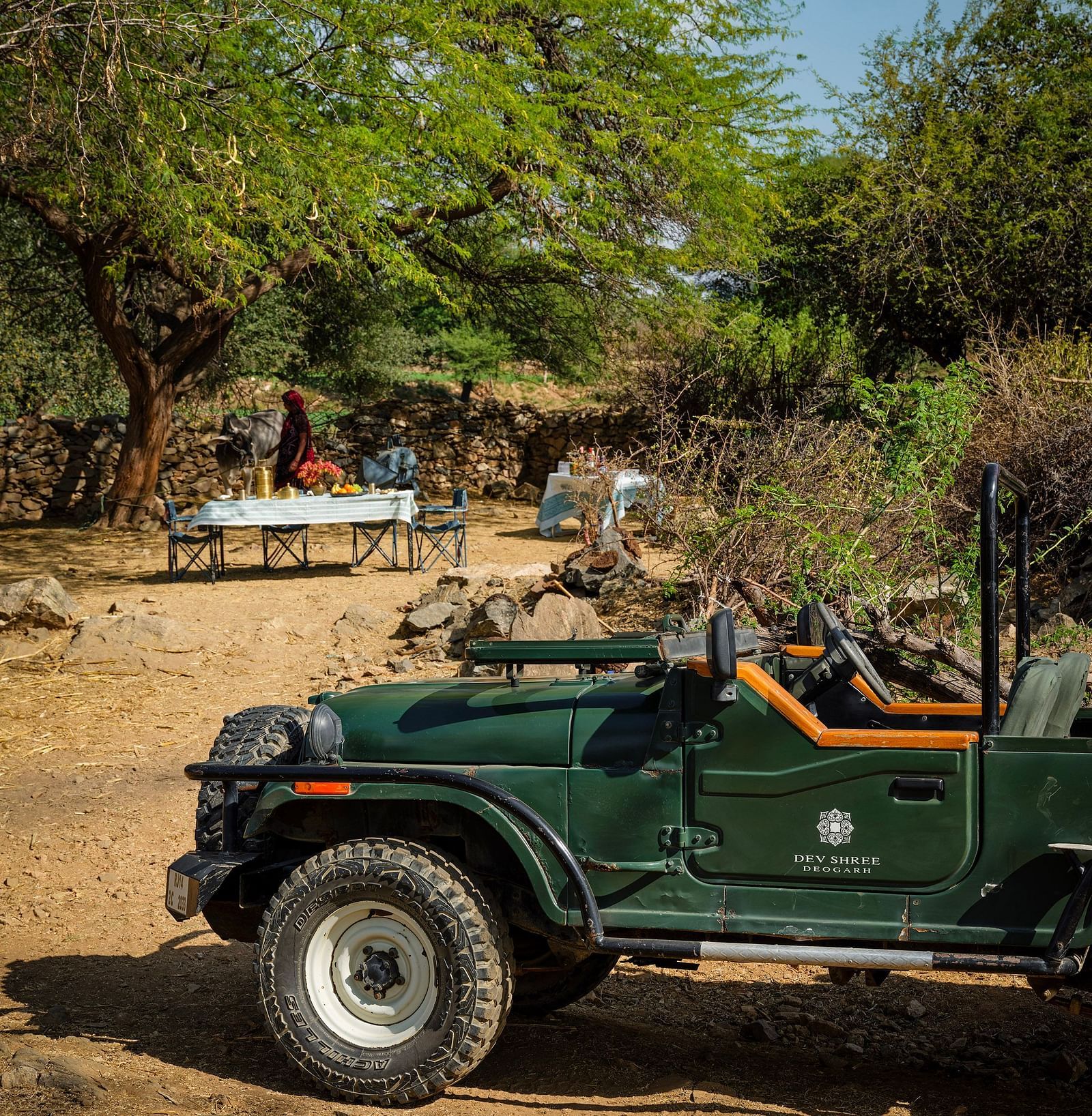 image of a green coloured safari jeep parked on a dry land at dev shree, deogarh