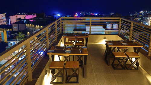 Image of Sky Deck rooftop restaurant featuring tables and chairs placed under the night sky