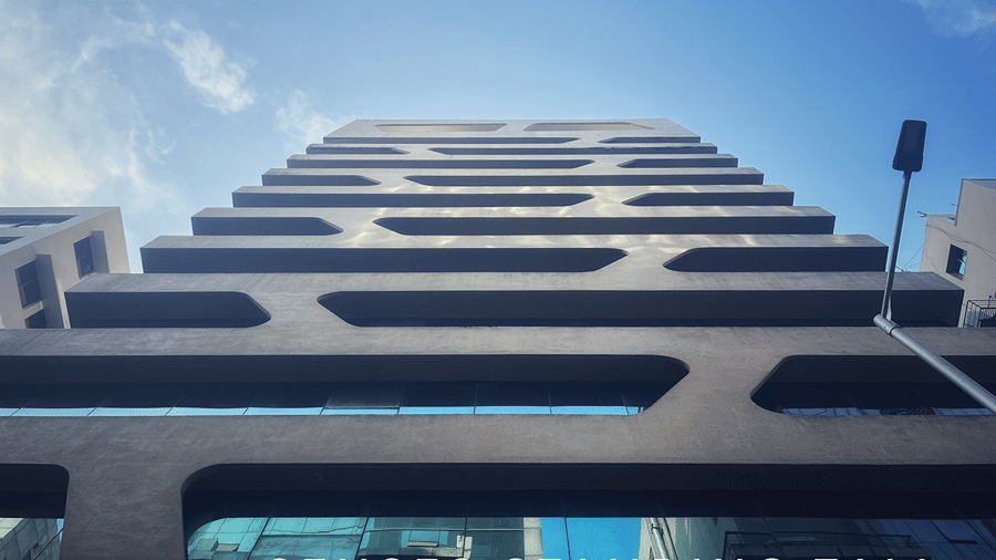 Facade of Senses Hotel featuring a tall building with a clear blue sky in the background.