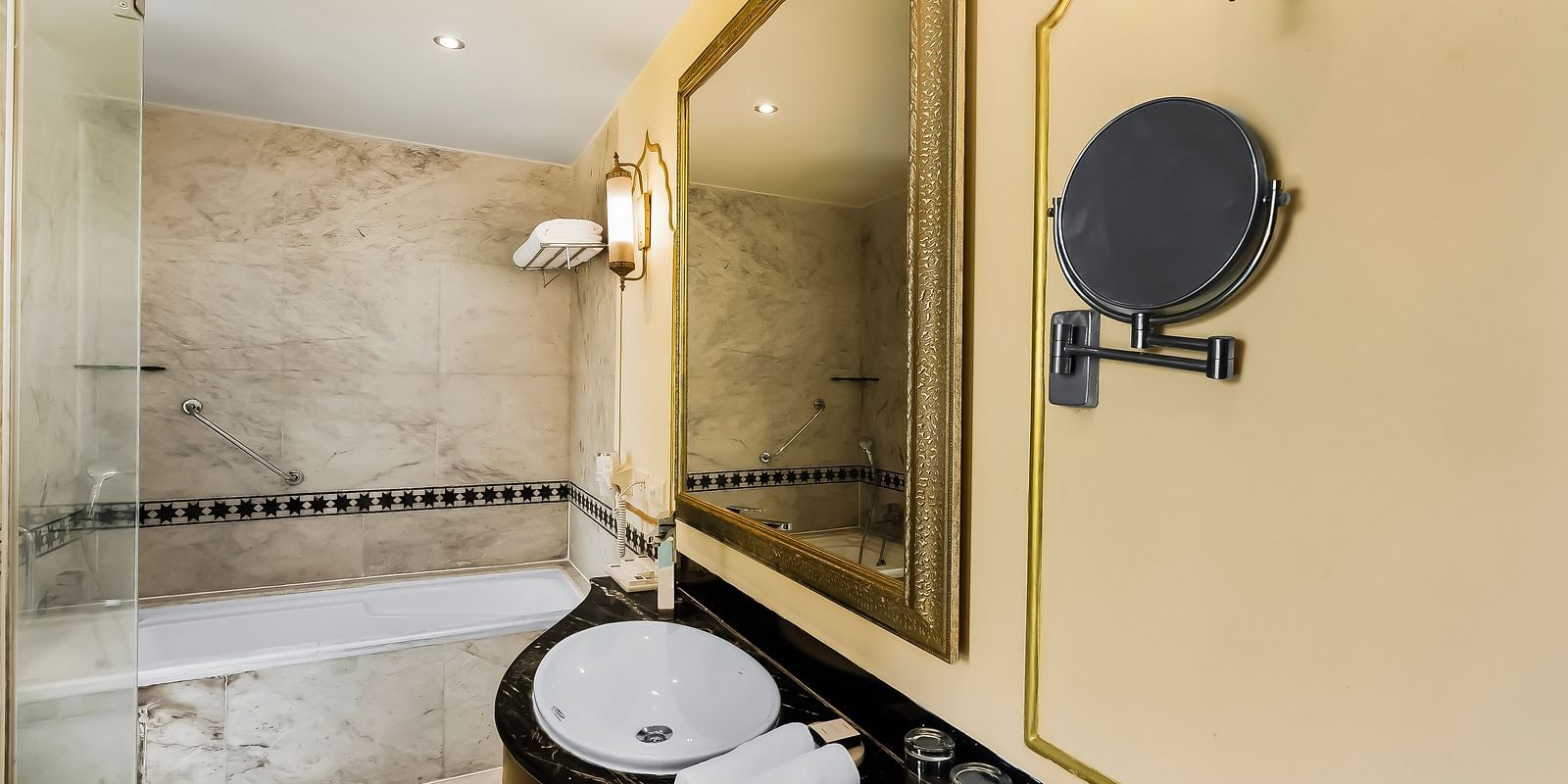 Modern glass-partitioned bathroom at Rajasthali Resort Jaipur with luxury amenities and sleek design elements.