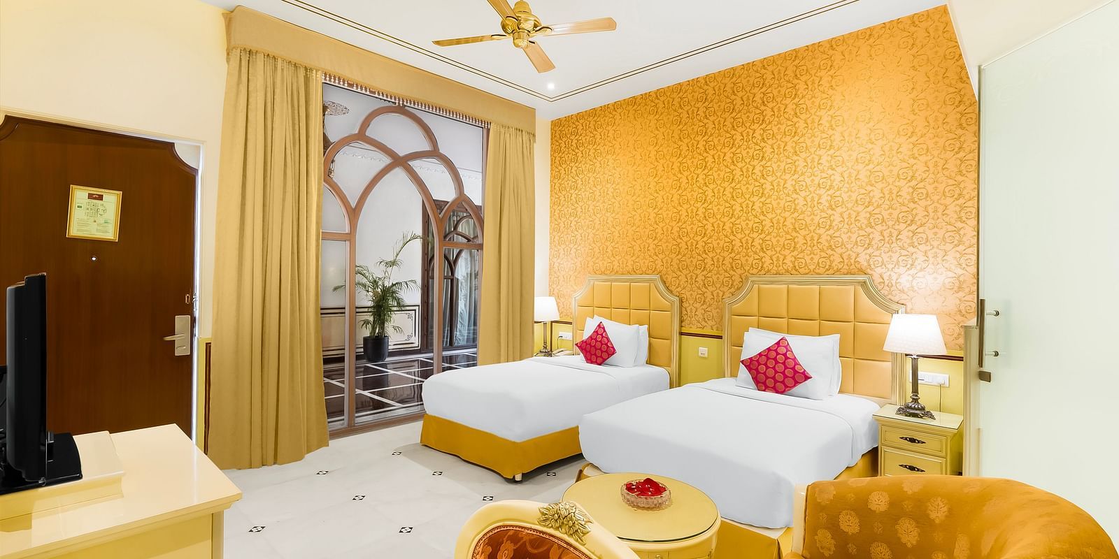 Twin-bed room with golden accents at Rajasthali Resort & Spa Jaipur, ideal for families or friends travelling together.