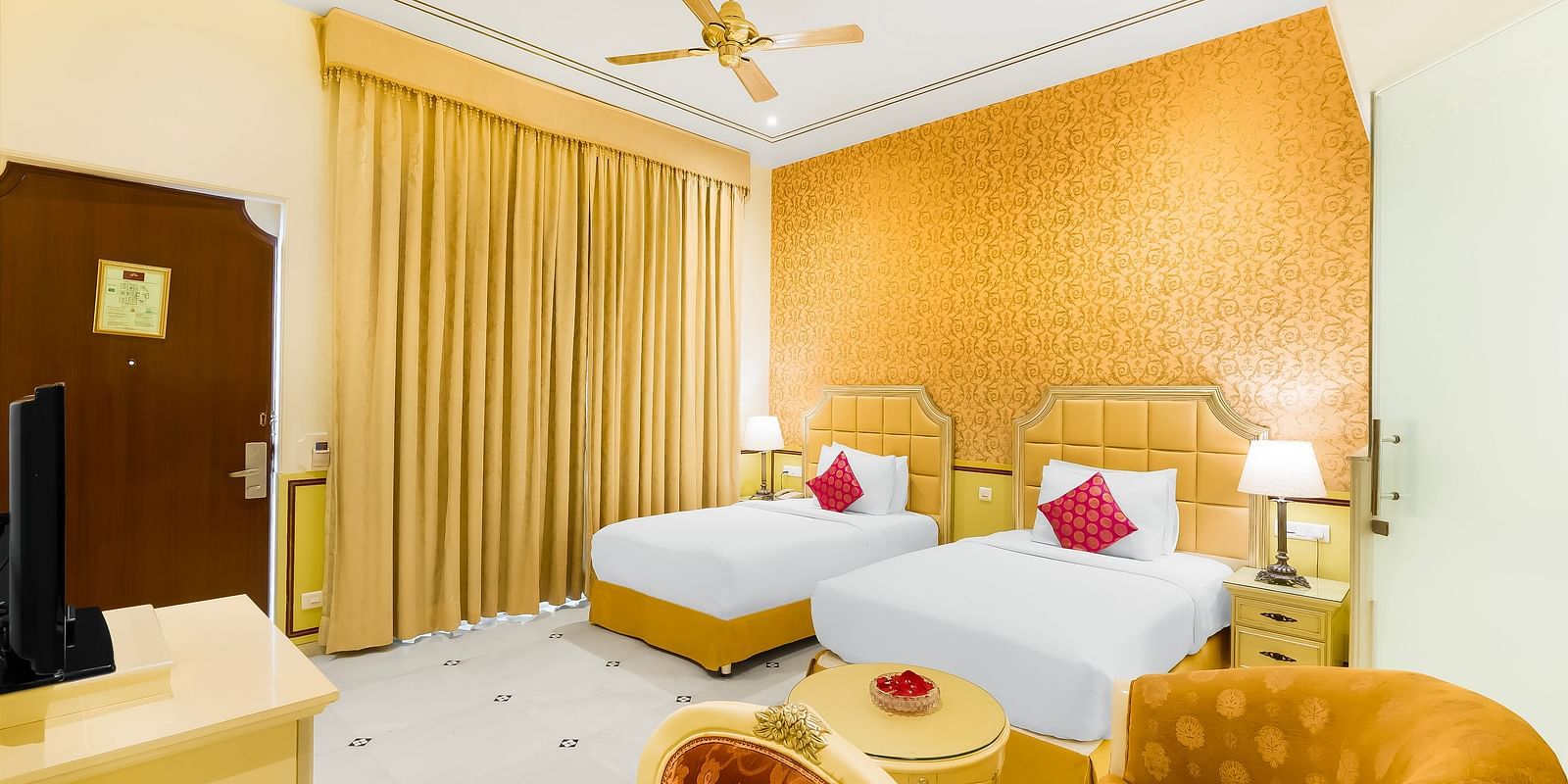 Twin-bedroom at Rajasthali Resort Jaipur with luxurious golden accents, elegant furniture, and traditional royal design.