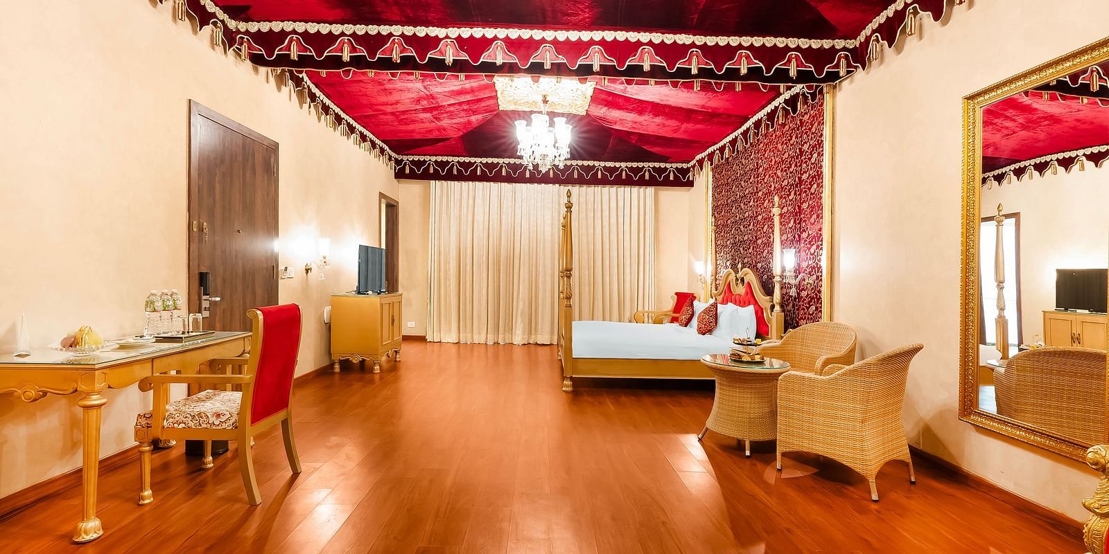 An overview of a room with a double bed, a study table and chairs seen - Rajasthali Resort & Spa, Jaipur.