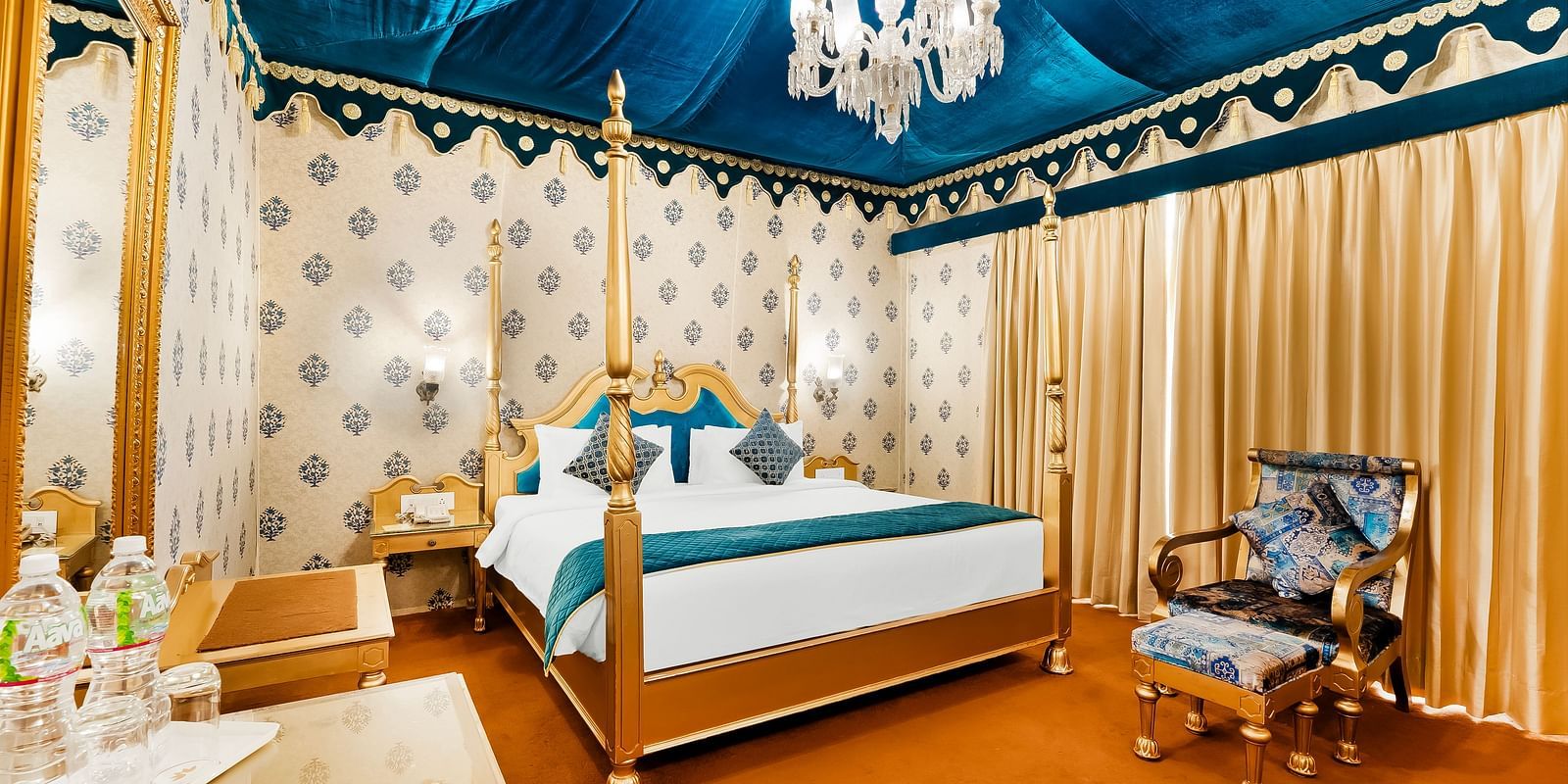 An overview of a tent with a double bed, a chair and a table inside it - Rajasthali Resort & Spa, Jaipur.