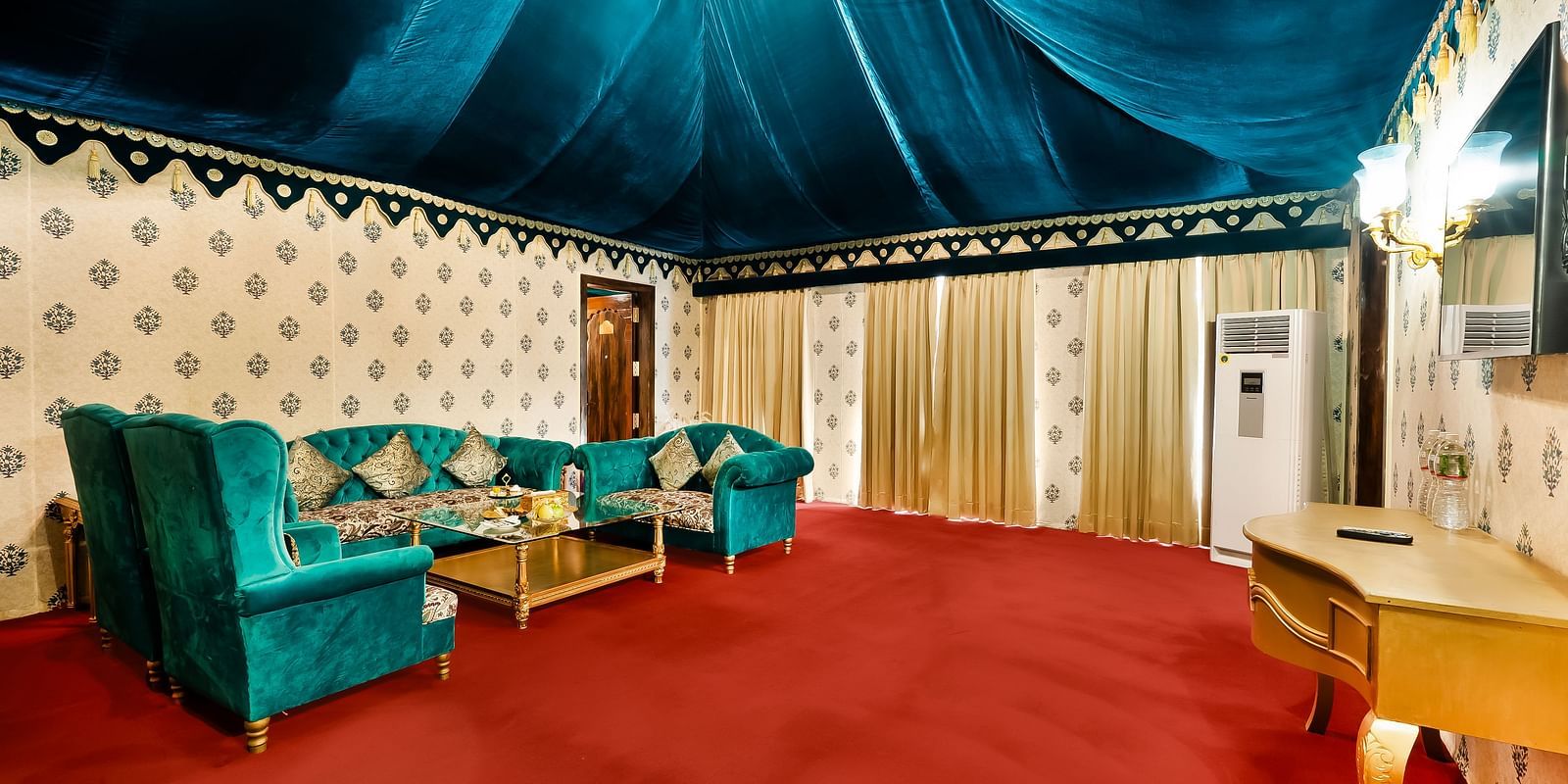 An overview of the living room with sofas, coffee table and a chandelier - Rajasthali Resort & Spa, Jaipur.