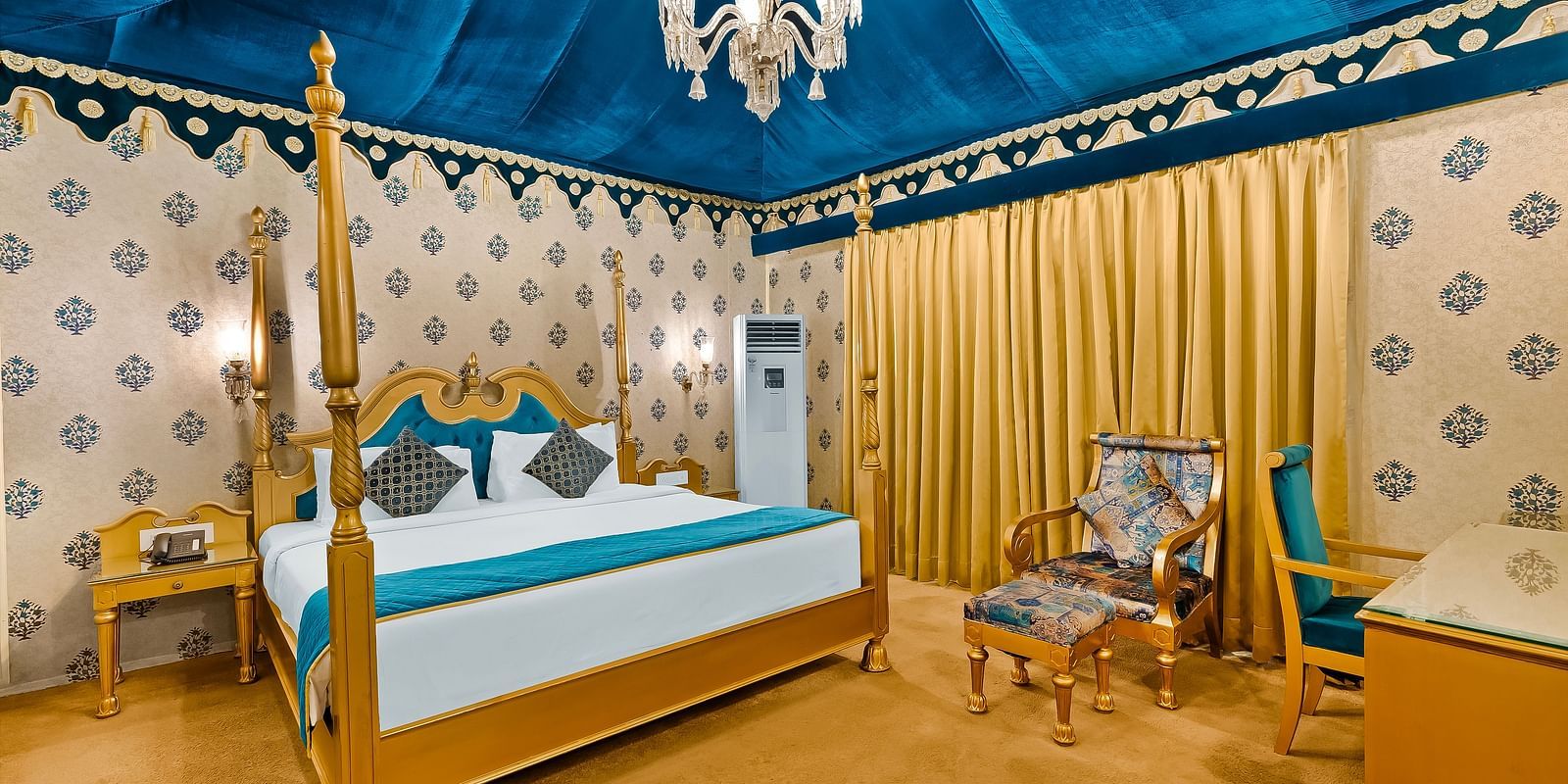 An overview of a tent with a double bed, water cooler and a chair inside - Rajasthali Resort & Spa, Jaipur.