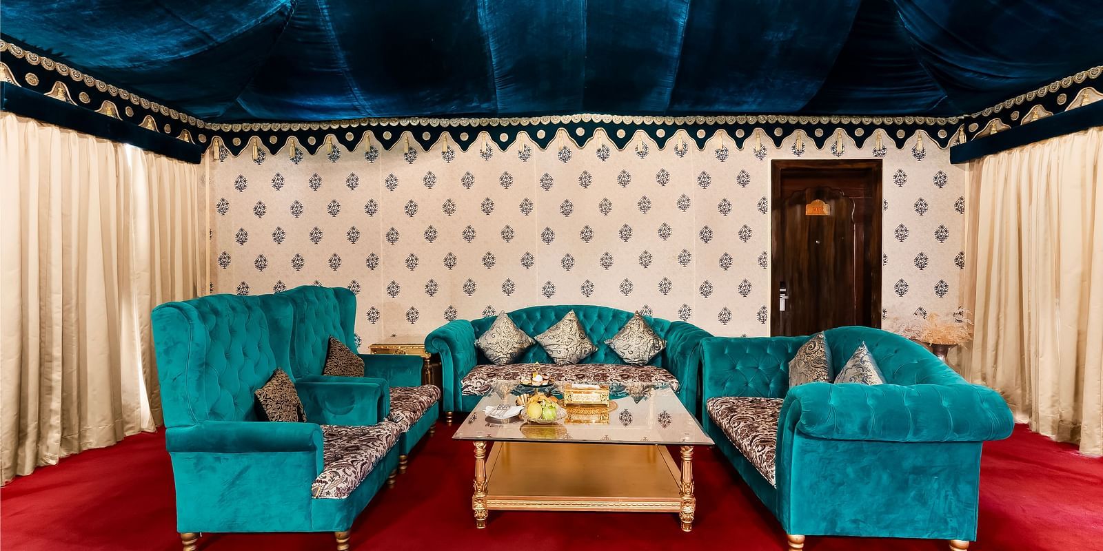 An overview of the living area inside a tent with sofas and a coffee table - Rajasthali Resort & Spa, Jaipur.
