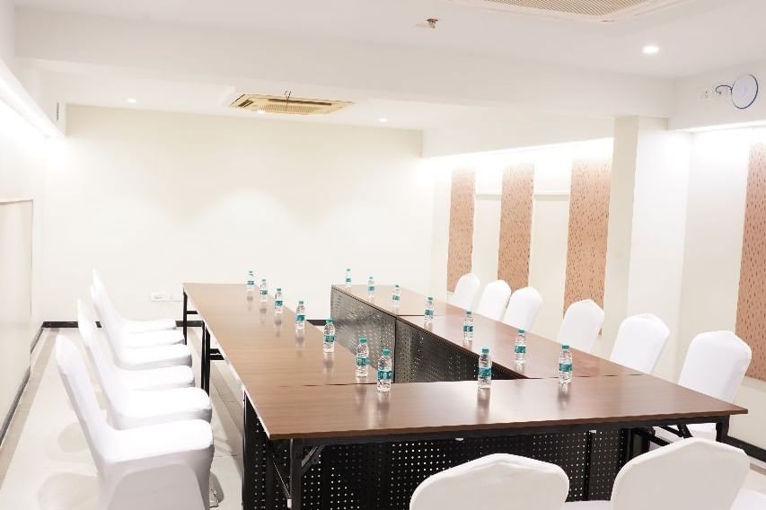 A long conference table with white covered chairs, arranged for a formal meeting in a brightly lit room at Shilton Dee Cee.