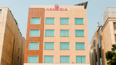 Facade of the Nemesia City Center in Gurugram featuring the hotel's entrance and its surrounding greenery.