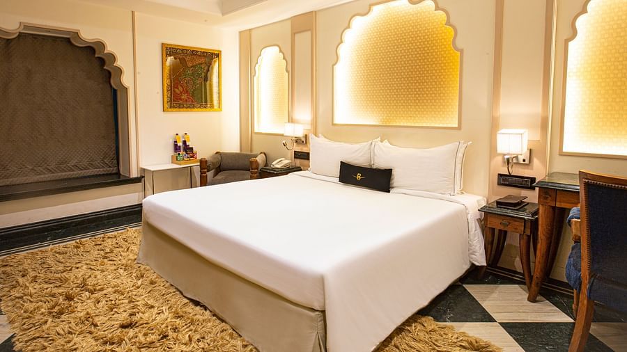 A side angle view of a Rajasthani-themed bedroom featuring a plush bed and beautiful decor, highlighting the rich colors and intricate details.