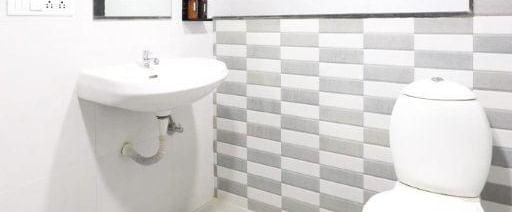 Full view of a brightly lit bathroom featuring a wash basin along with a commode in the corner at Pravasa Ahmedabad.